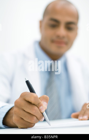 Doctor writing a prescription, focus on hand in the foreground Stock Photo