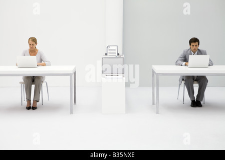 Colleagues in office using laptop computers, printer between them with graphic of document Stock Photo