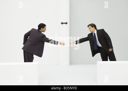 Two businessmen reaching to shake hands, arrow between them Stock Photo