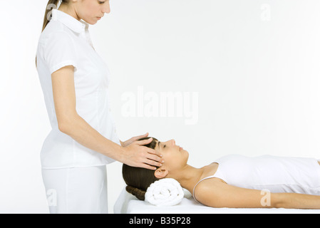 Woman lying on her back receiving head massage, eyes closed Stock Photo