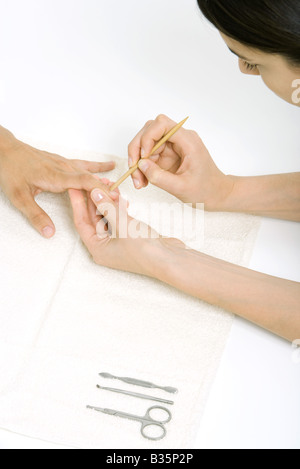 Woman using a cuticle pusher to give a manicure Stock Photo