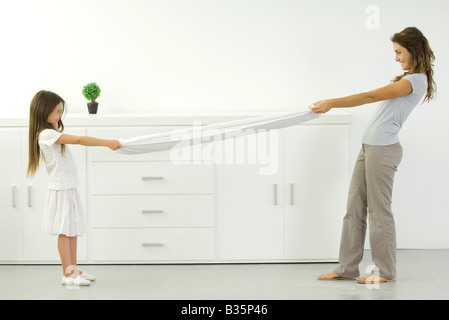 Mother and daughter pulling on opposite ends of sheet Stock Photo