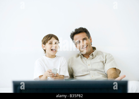 Father and son watching TV together, boy holding remote Stock Photo