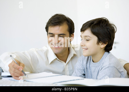 Father helping his son do homework, both smiling Stock Photo