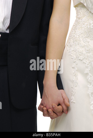 Mid section view of a newlywed couple holding each other's hands Stock Photo