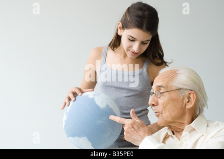 Grandfather and granddaughter looking at globe together