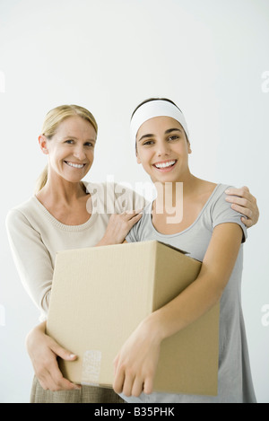 Young female holding cardboard box, mother holding her shoulders Stock Photo