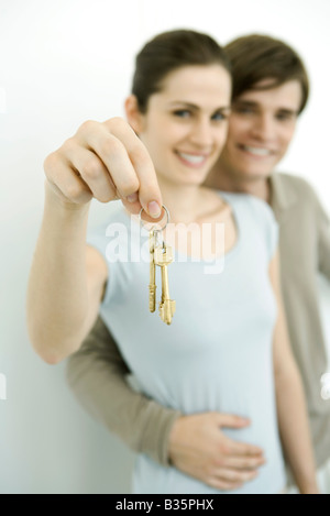 Young couple smiling at camera, woman holding up set of keys Stock Photo