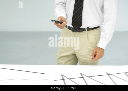 Businessman using cell phone, cropped view of mid section Stock Photo