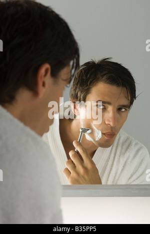 Man shaving, looking at self in mirror Stock Photo
