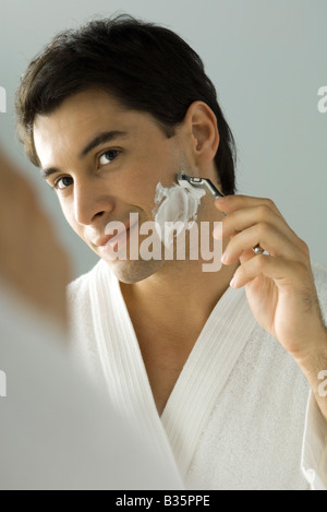 Man shaving, smiling at self in mirror Stock Photo