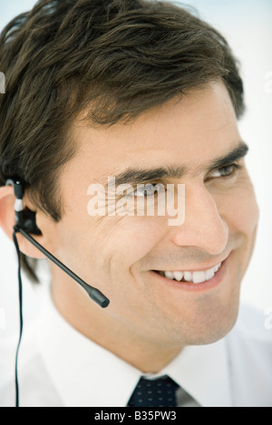 Man wearing headset, smiling, looking away Stock Photo