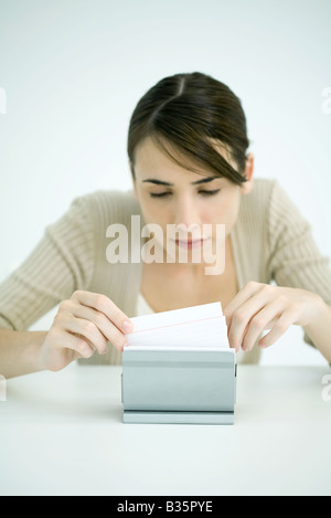 Young woman looking through box of index cards Stock Photo
