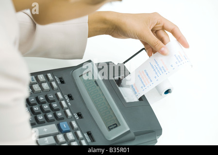 Businesswoman using adding machine, holding printout, cropped view Stock Photo