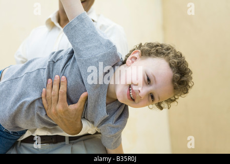 Boy pretending to be a plane, being held by his father Stock Photo