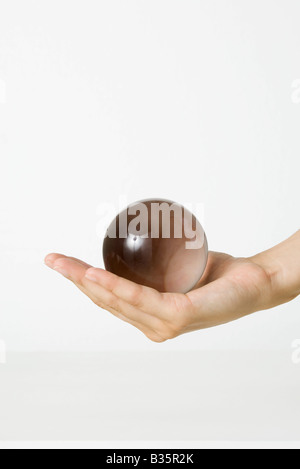 Cupped hand holding crystal ball, cropped view Stock Photo