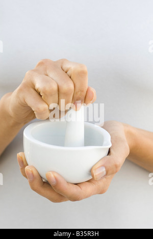 Woman using mortar and pestle, close-up, cropped view Stock Photo