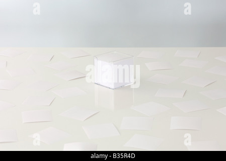 Scattered sheets of paper around a stack of paper in plastic container Stock Photo