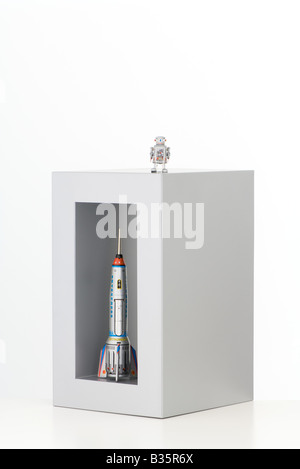 Toy robot standing on top of a box with a toy rocket standing up in it Stock Photo
