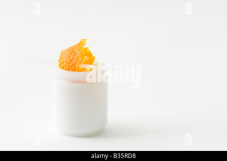 Orange zest in small jar, tiny plastic spatula jutting out Stock Photo