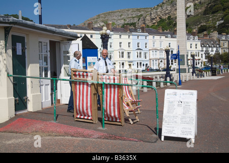 Llandudno Conwy North Wales UK May A couple of men hiring out deck chairs on promenade of this popular Welsh seaside resort town Stock Photo