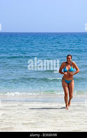 'Red Sea' beach near Marsa Alam Egypt with woman wearing bikini walking out of the sea Stock Photo