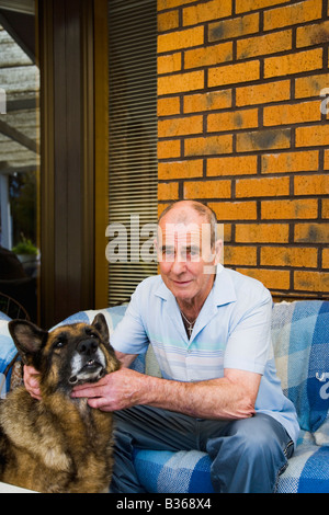 Senior man sitting on chair with dog Stock Photo