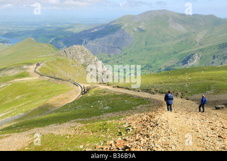 Two people walking up the llanberis path away from Clogwyn railway station on the steep upper slopes of Mount Snowdon Stock Photo