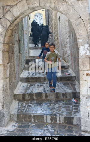 Muslim Women Wearing Chadors Going Upstairs Boys Coming Down in the Old City in Aleppo Syria Stock Photo