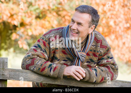 Man outdoors at park leaning on fence smiling (selective focus) Stock Photo