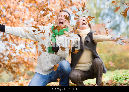 Couple outdoors playing in leaves and smiling (selective focus) Stock Photo