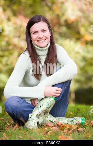 Woman sitting outdoors smiling (selective focus) Stock Photo