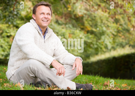 Man sitting outdoors smiling (selective focus) Stock Photo
