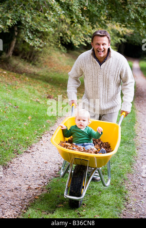 Father pushing baby son in wheelbarrow Stock Photo