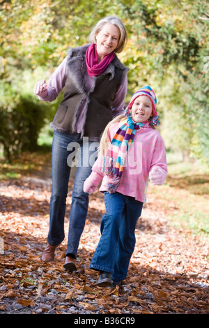 Grandmother and granddaughter walking on path outdoors smiling (selective focus) Stock Photo