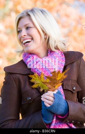 Woman outdoors in park holding leaf smiling (selective focus) Stock Photo