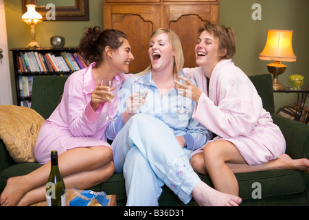 Three woman in night clothes sitting at home drinking wine Stock Photo