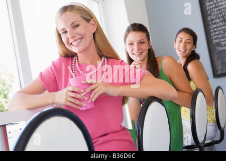 Three young women having a cold drink in a cafeteria Stock Photo