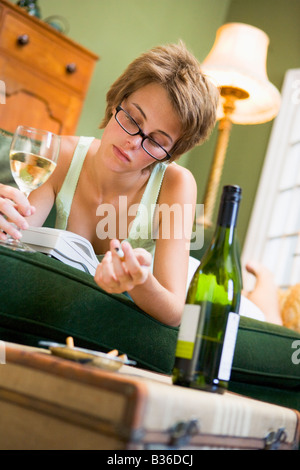 Young woman at home smoking and drinking wine by telephone Stock Photo