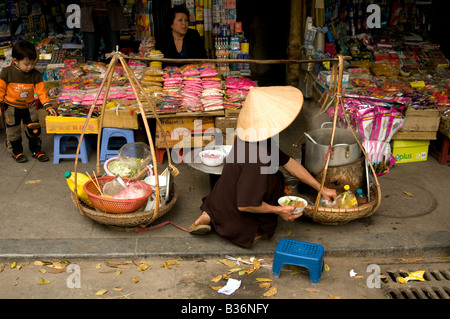 Back view of a mobile restaurant woman making soup on the pavement in Hanoi Vietnam Stock Photo