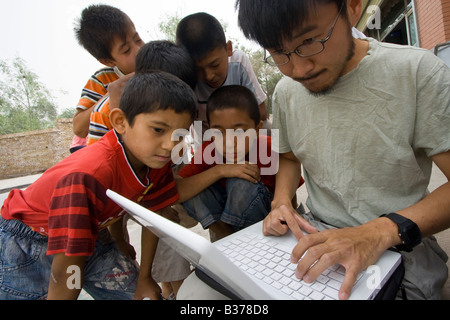 Chinese Boys Watching on as a Korean American Tourist Uses a Computer in Kashgar China Stock Photo