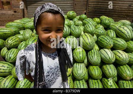 Young Uyghur Girl in front of Watermelons in the Market in Kashgar in Xinjiang Province in China Stock Photo