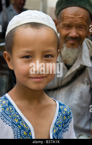 Uyghur Chinese Boy and Grandfather in the Sunday Market in Hotan Xinjiang Province China Stock Photo