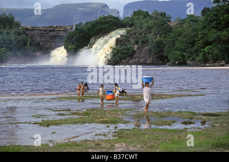 Pemon Indian women wash clothes by hand on the Caroni River near a large waterfall in Canaima National Park Stock Photo