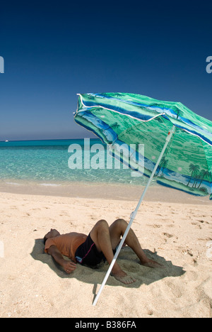 A man relaxing under umbrella on the beach Stock Photo
