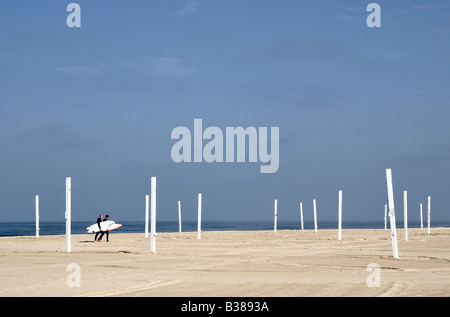 Surfers on an empty beach with volleyball courts, early morning in Hermosa Beach CA Stock Photo