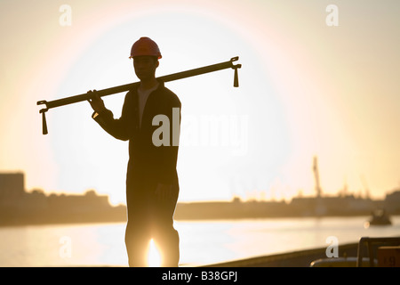 Asian male dock worker holding pipe Stock Photo