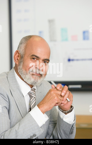 Portrait of businessman holding pen at desk in office Stock Photo - Alamy