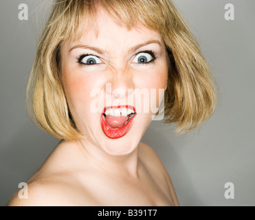 Portrait of young blonde caucasian woman who is looking at the viewer with angry expression Stock Photo