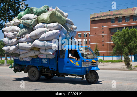 Overloaded blue tuk-tuk three wheeled auto rickshaw vehicle piled high ...